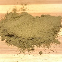a pile of green powder on a wooden table